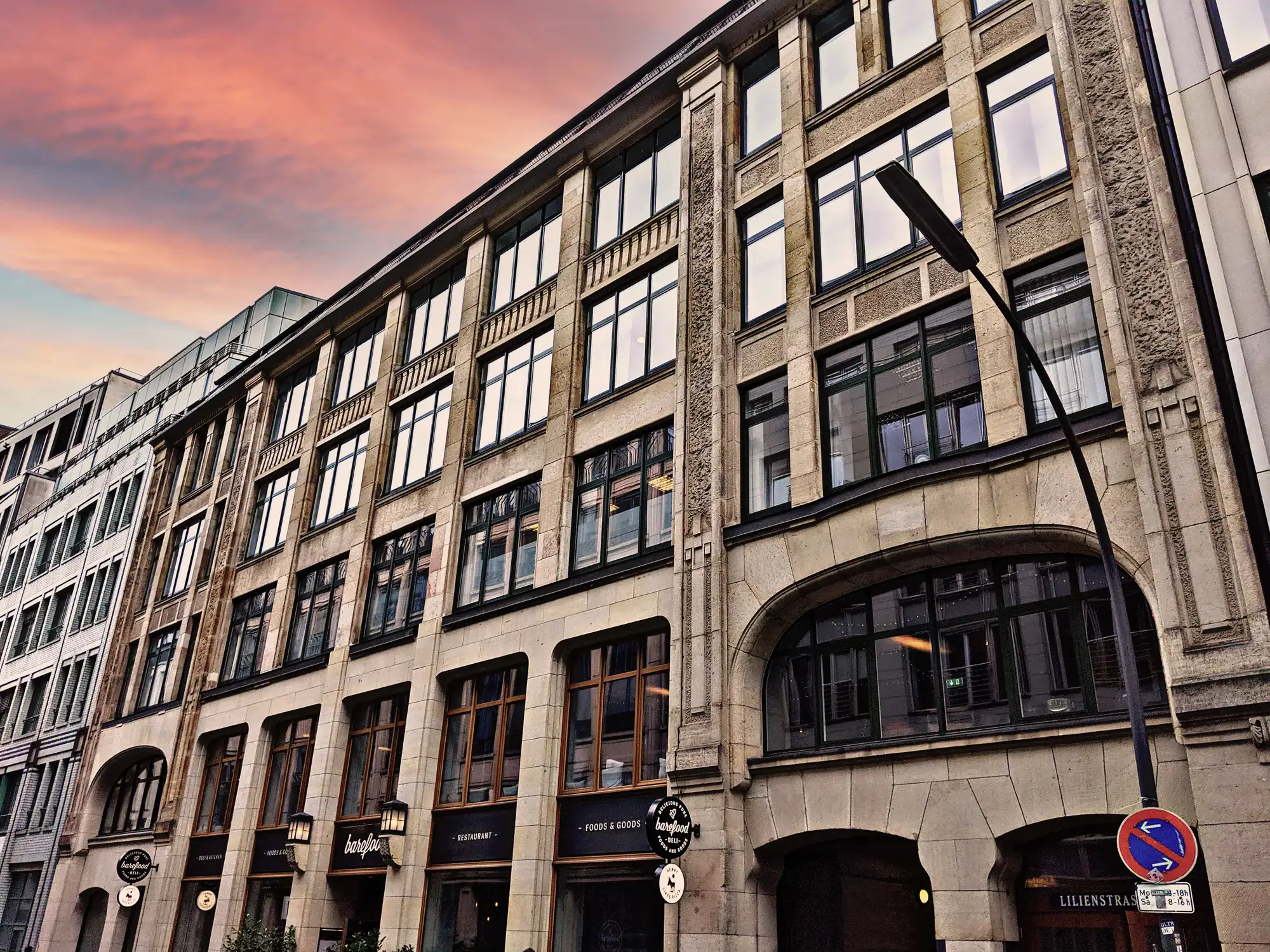 Bürogebäude mit großen Fenstern und urbaner Architektur bei Sonnenuntergang.