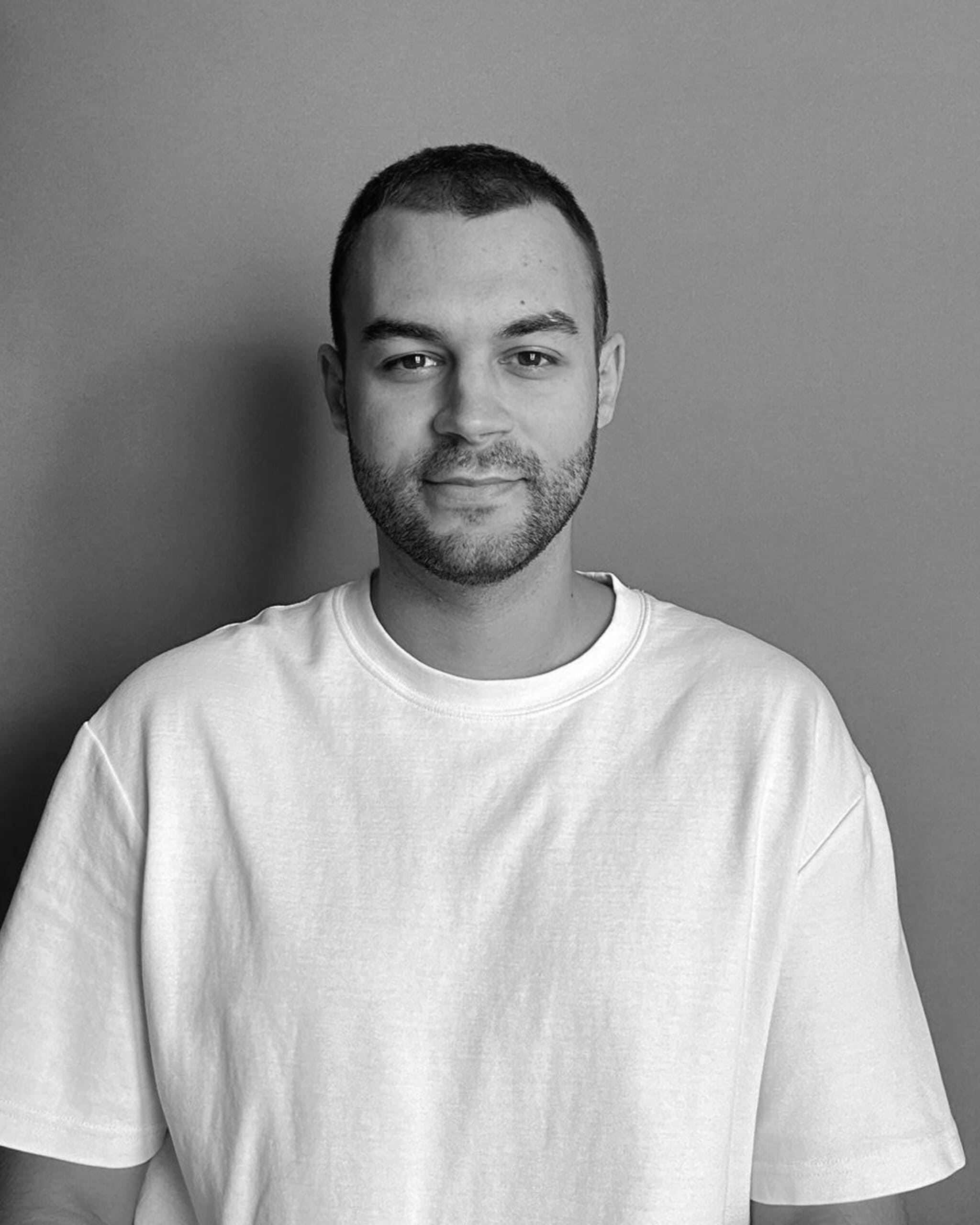 Man in white t-shirt against a grey background.