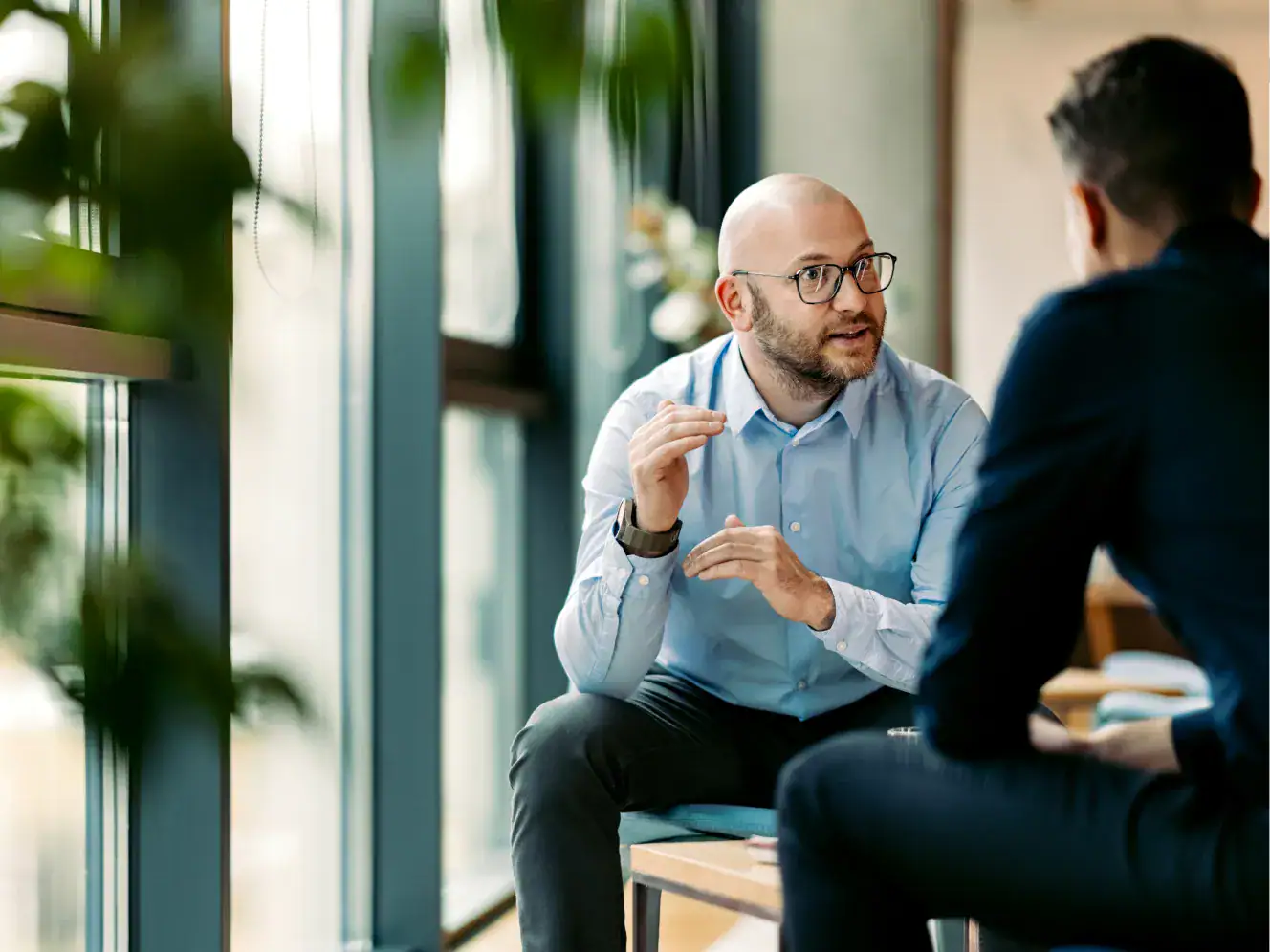 Hände eines Mannes, der im Gespräch mit einem anderen Mann sitzt, im modernen Büro.