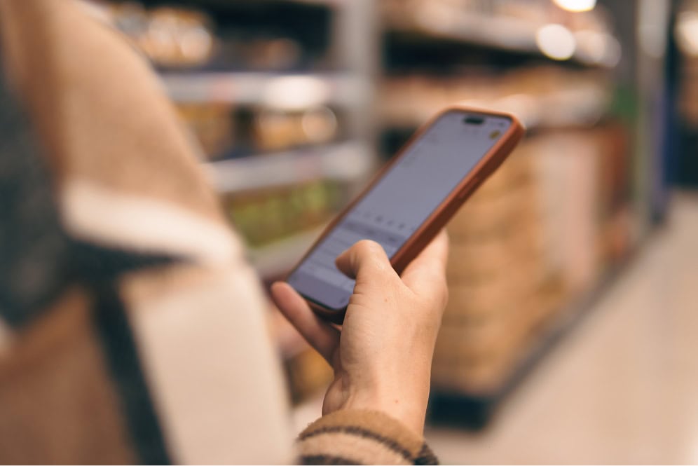 Ein Mensch hält ein Smartphone in der Hand in einem Geschäft.