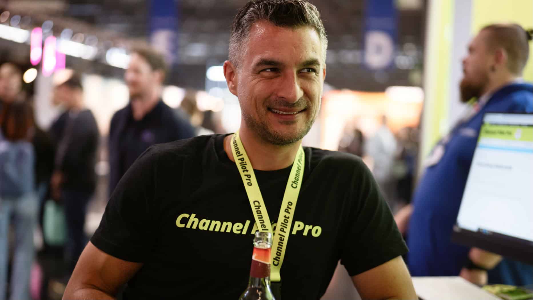 Mann mit Channel Pro T-Shirt bei einer Messe, lächelnd und im Gespräch.