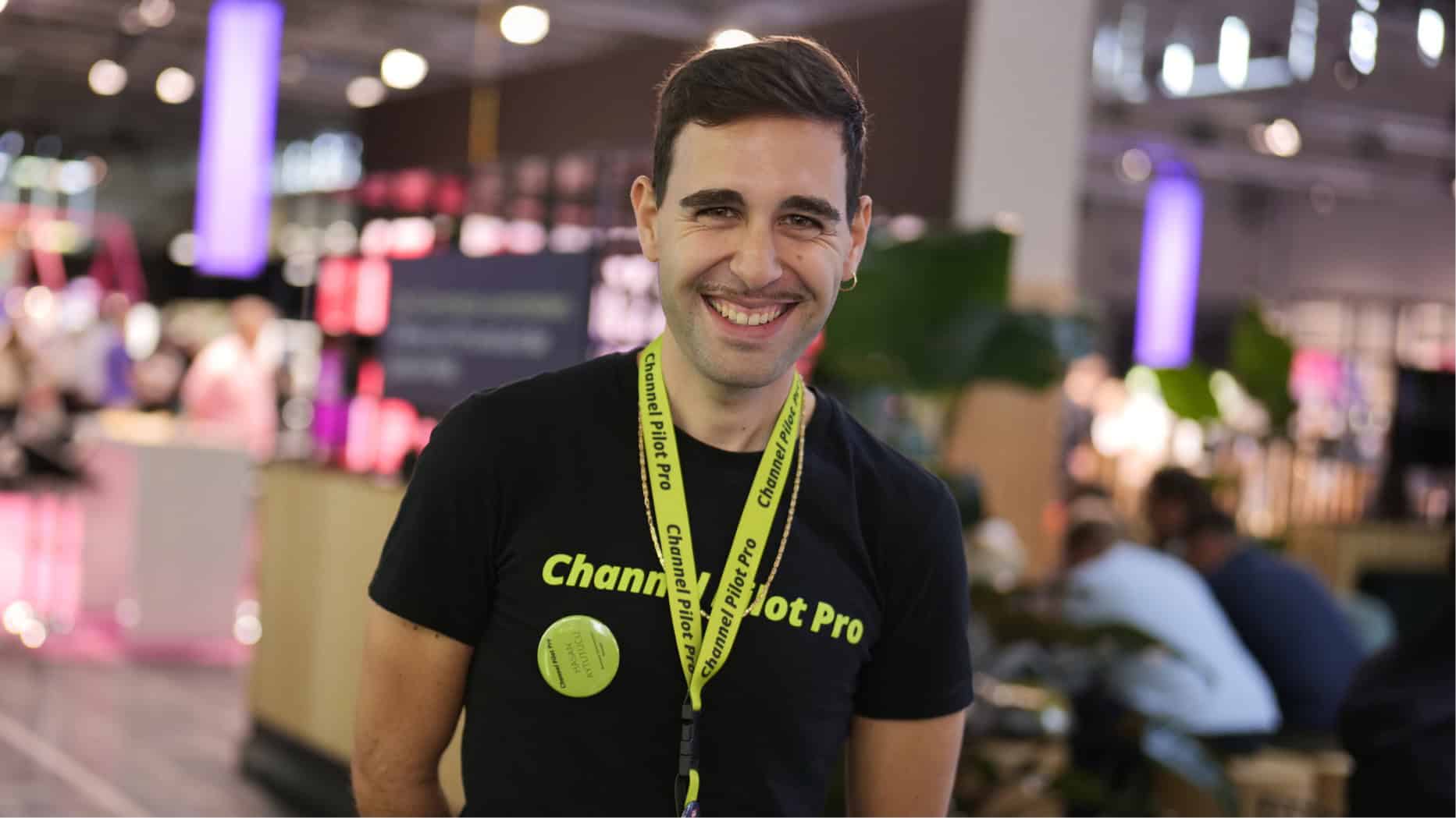 Jeune homme joyeux avec un tour de cou sur une foire, souriant à l'appareil photo.