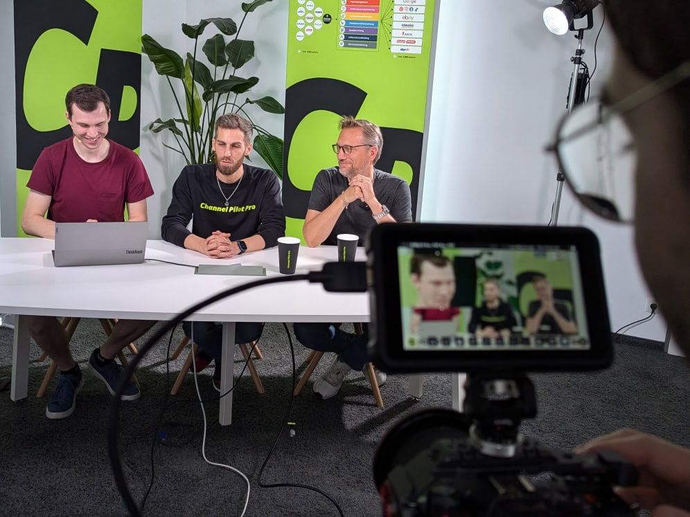 Drei Männer bei einem Interview oder einer Diskussion vor einer Kamera.
